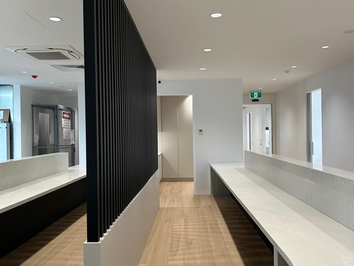 Curved pale reception counters and a black slatted screen at the Bayside medical centre.