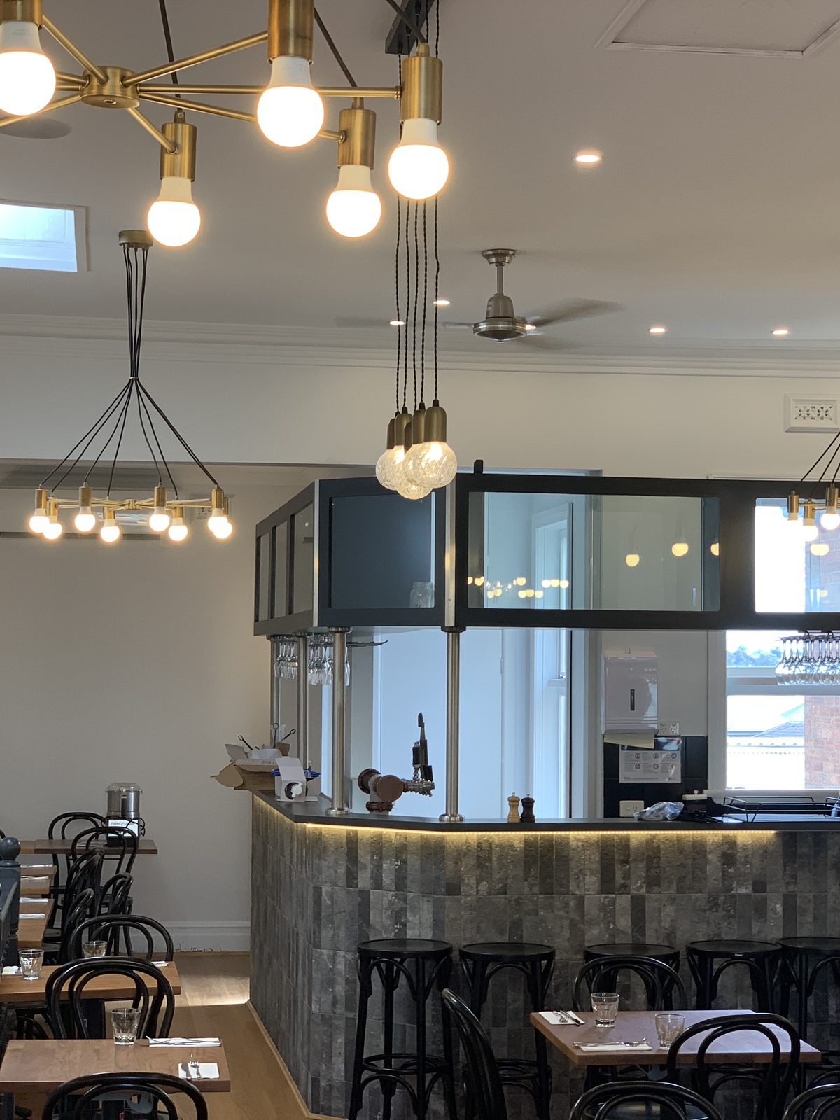 Upstairs restaurant bar with a tiled counter front, a glazed overhead gantry and brass pendant lights, inner Melbourne.