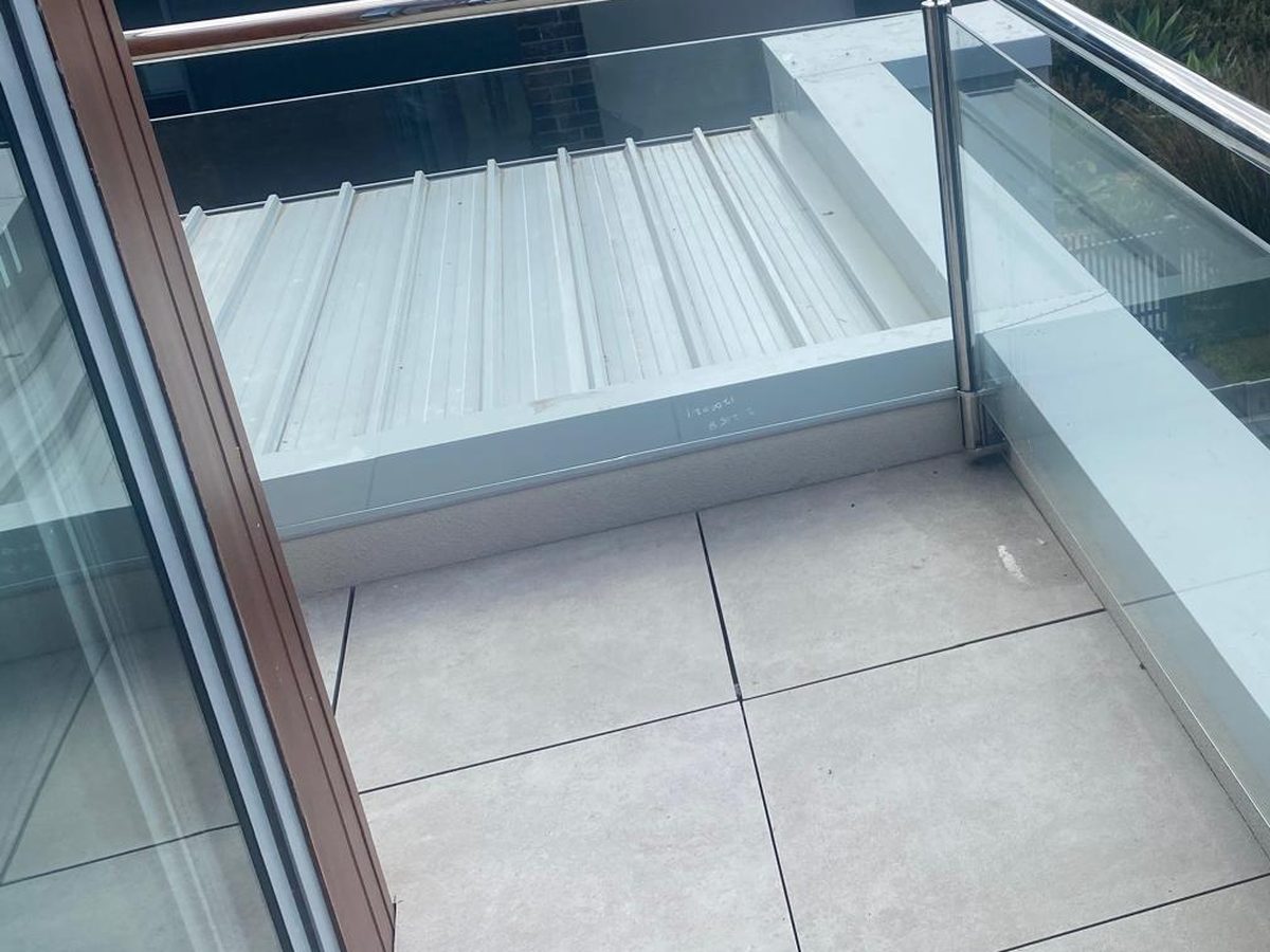 The reinstated balcony with new tiling, a frameless glass balustrade and a stainless handrail after rectification, Mornington Peninsula.