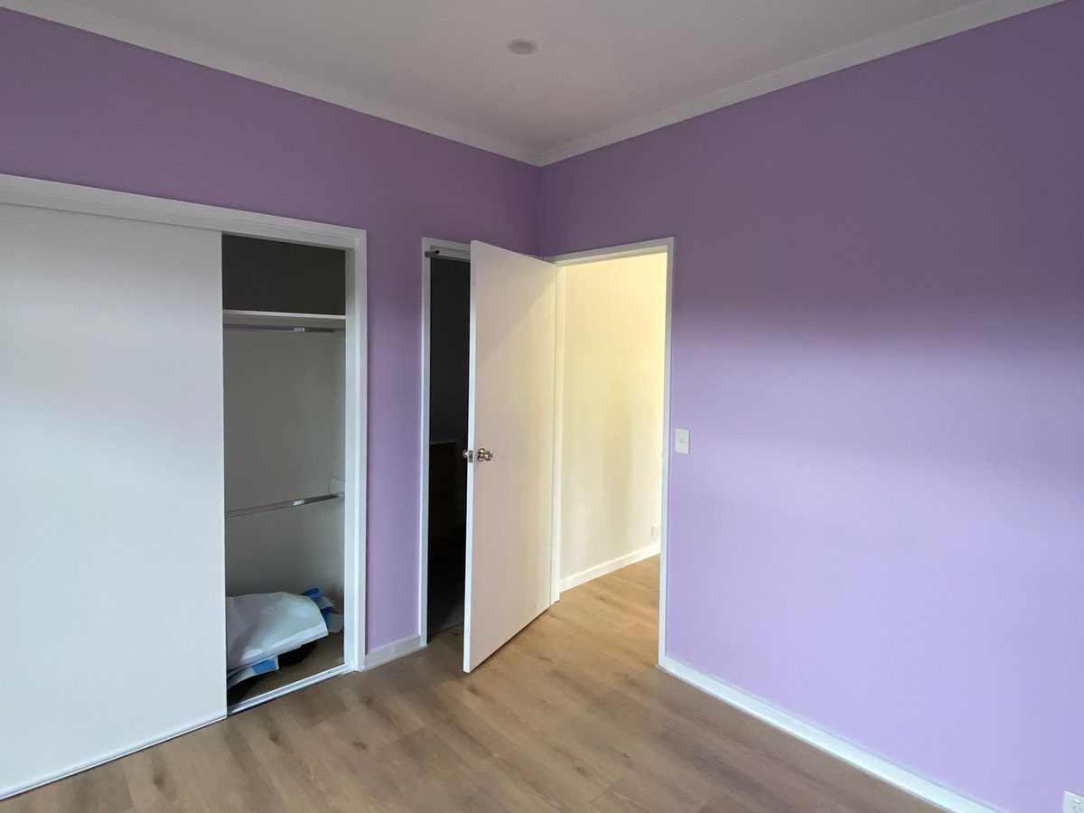 A completed bedroom with painted walls, timber-look flooring and a built-in robe with sliding doors, Melbourne’s south-east.