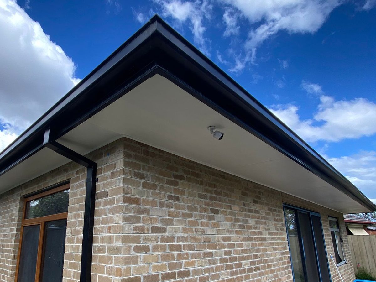 The new extension corner in cream brick with a lined eaves soffit, finished fascia and gutter and the downpipe run to the stormwater riser, Melbourne’s south-east.