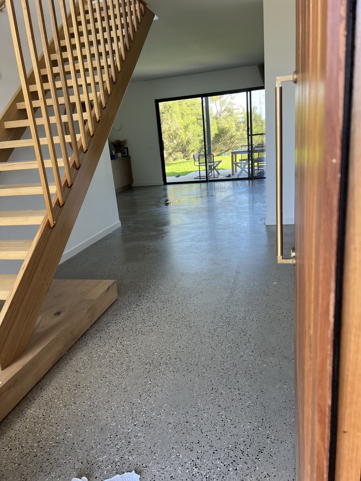 Entry with an open timber front door, a timber stair and a polished concrete floor looking through to rear glazing, Mornington Peninsula.