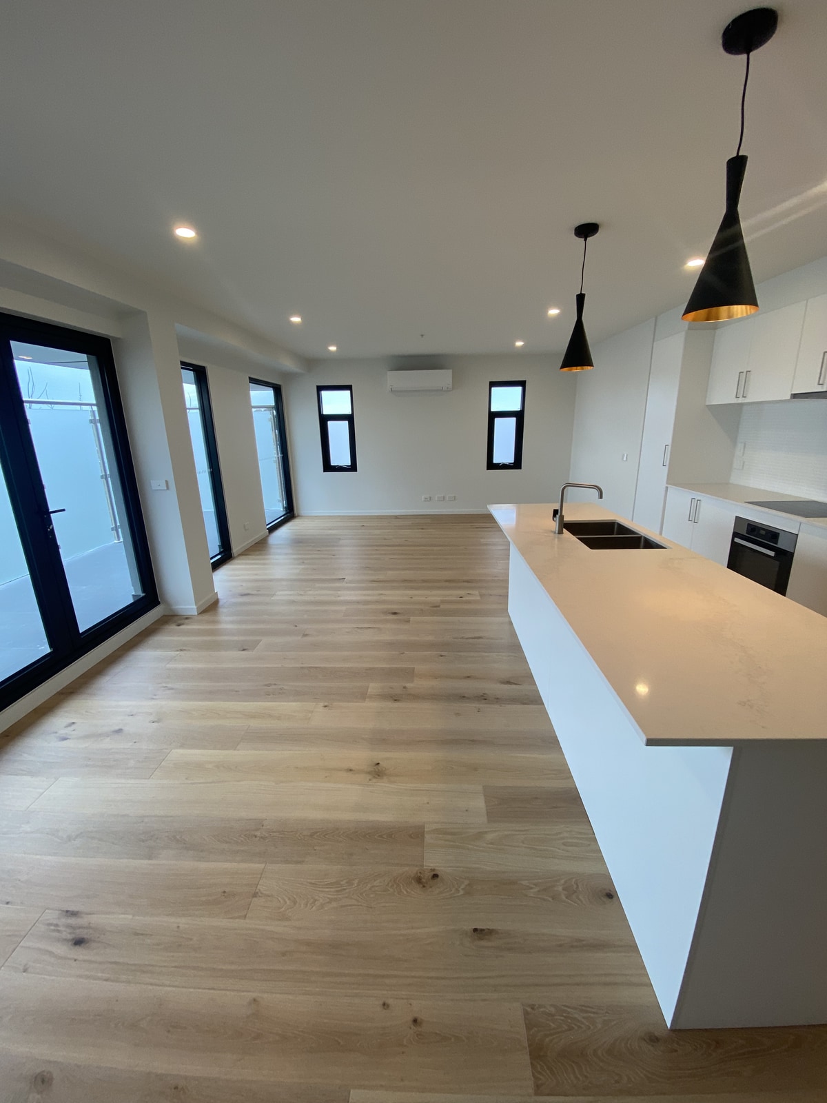 Finished apartment interior with kitchen, timber flooring and balcony outlook in Melbourne’s inner north-west.