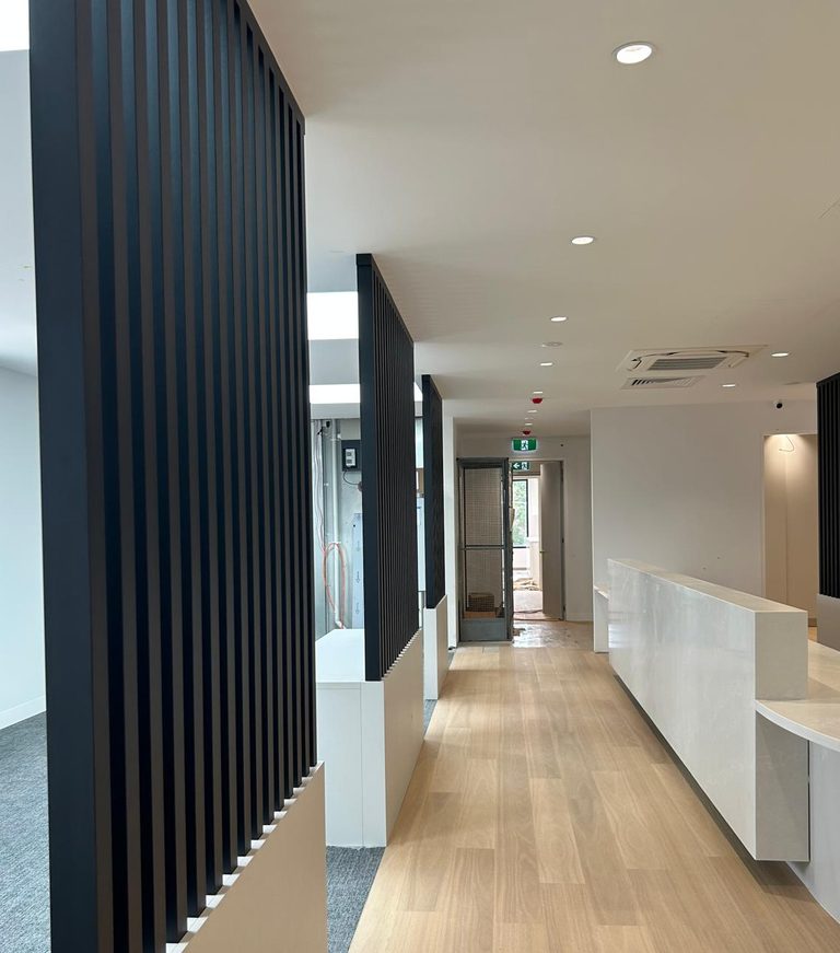 Completed commercial interior with slatted timber screen and fitted reception joinery.