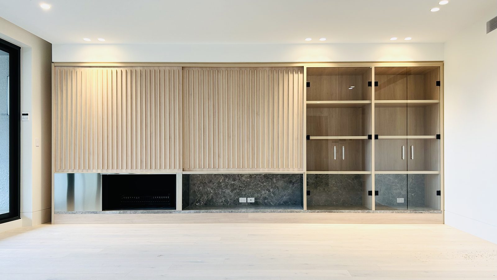 Fitted timber slat wall, open shelving and stone joinery in a completed apartment interior, Brighton.